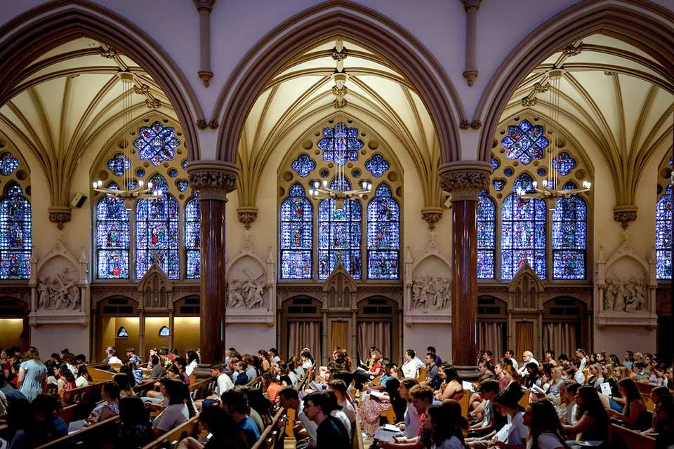 Interior of college church full of students attending mass